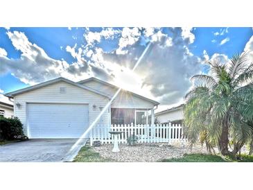 Charming home with a white picket fence, a well-manicured lawn, and a tropical palm tree in the front yard at 1650 Duran Dr, The Villages, FL 32162