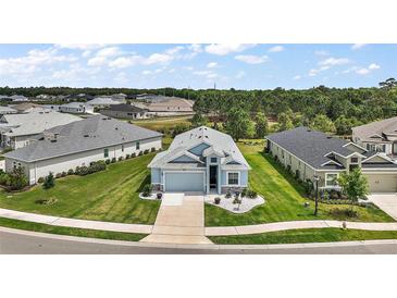Beautiful aerial view of a single-Gathering home with lush green landscaping, a driveway, and neighboring houses at 1966 Wallingford Loop, Mount Dora, FL 32757