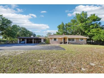Charming single-story home featuring a large driveway, well-manicured lawn, and mature shade trees at 23519 State Road 44, Eustis, FL 32736