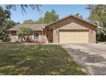 Charming brick home with a well-manicured lawn and attached two-car garage at 35138 Silver Oak Dr, Leesburg, FL 34788