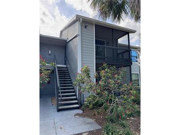 Two-story condo building with gray siding, black railings, and a stairwell leading to the upper units at 3748 Idlebrook Cir # 202, Casselberry, FL 32707
