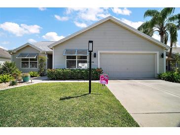 Charming single-story home featuring a well-manicured lawn and a two-car garage at 419 Aldama Ave, The Villages, FL 32159