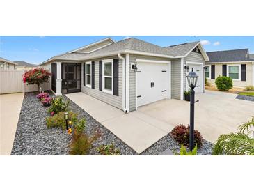 Charming single-story home featuring a two-car garage, landscaped front yard, and a screened-in porch at 5726 Leboeuf Ln, The Villages, FL 32163