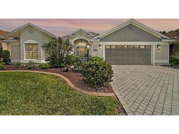 Charming single-story home with a well-manicured lawn and a brick-paved driveway at 685 Winifred Way, The Villages, FL 32162