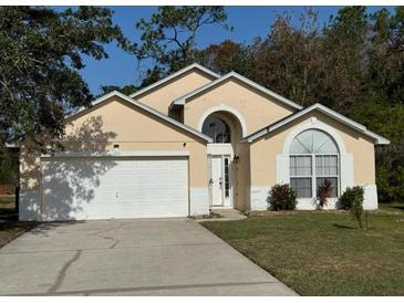 Charming one-story home featuring an attached two-car garage, arched windows, and a well-maintained lawn at 1040 Soaring Eagle Ln, Kissimmee, FL 34746