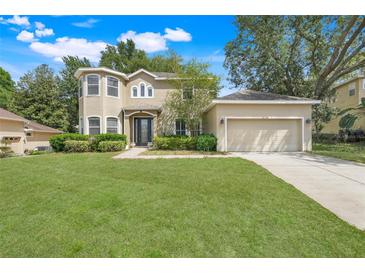 Charming two-story home featuring a manicured lawn, attached two-car garage, and complemented by mature trees at 12346 Lake Valley Dr, Clermont, FL 34711