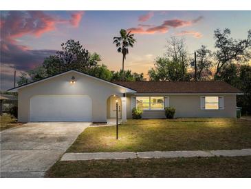 Charming single-story home featuring an attached garage and well-maintained front lawn and inviting curb appeal at 1415 S Baton Dr, Deltona, FL 32725