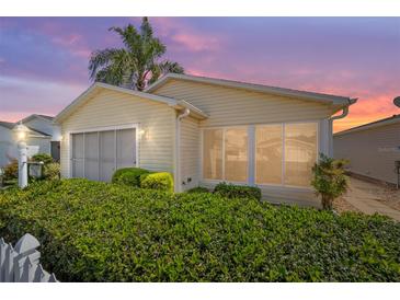 Charming home exterior featuring manicured hedges, screened garage, and inviting curb appeal at sunset at 1706 Moreno Pl, The Villages, FL 32159