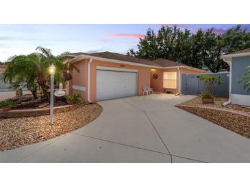 Charming single-story home featuring a well-maintained lawn, attached garage, and inviting curb appeal at 1814 Marquez Loop, The Villages, FL 32159