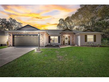 Charming single-story home featuring a manicured lawn, brick accents, and a two-car garage at 25273 Lost Oak Cir, Leesburg, FL 34748