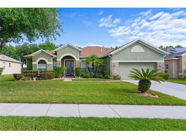 Landscaped front yard and exterior of a single-story home with stone accents and a two-car garage at 3440 Tumbling River Dr, Clermont, FL 34711