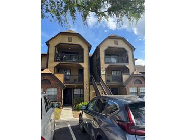 Apartment complex with balconies, stairs, and parking area with neutral tones and brick accents at 420 Forestway Cir # 206, Altamonte Springs, FL 32701