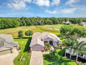 Stunning aerial view of a home showcasing lush landscaping and a beautiful golf course backdrop on a sunny day at 4247 James River Cir, Leesburg, FL 34748