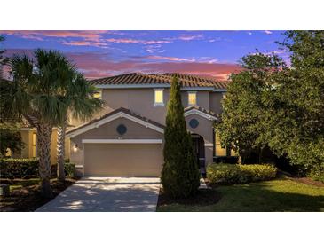 Charming two-story home showcasing a well-manicured lawn, mature trees, and a spacious two-car garage at 4328 Acorn Ct, Davenport, FL 33837