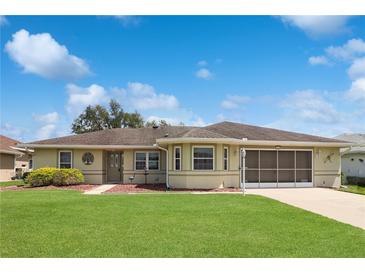 Charming single-story home featuring a well-manicured lawn and a screened-in garage, offering both curb appeal and functionality at 4723 Saint Andrews Arc, Leesburg, FL 34748