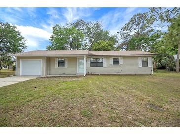 Charming single-story home featuring an attached garage and well-maintained front lawn at 74 Stone Haven Ct, Leesburg, FL 34788