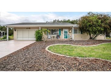 Charming single-story home with a well-manicured lawn, inviting front porch, and attached garage at 10689 Se 174Th Loop, Summerfield, FL 34491