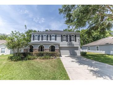 Charming two-story home with a well-manicured lawn and grey exterior paint, offering a welcoming curb appeal at 1704 Hoofprint Court, Fruitland Park, FL 34731