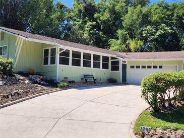 Charming home featuring an attached garage, large driveway, and ample greenery surrounding the property at 1765 Hilltop Dr, Mount Dora, FL 32757
