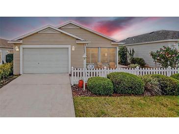 Charming single-story home with a well-maintained lawn, white picket fence, and attached garage at 1833 Endsley Ct, The Villages, FL 32162