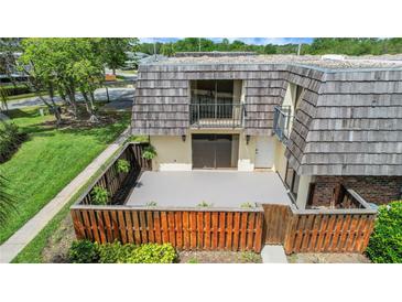 Charming townhouse featuring a private patio with wood fence, lush landscaping, and second story balconies at 2934 Tangerine Ct, Leesburg, FL 34748