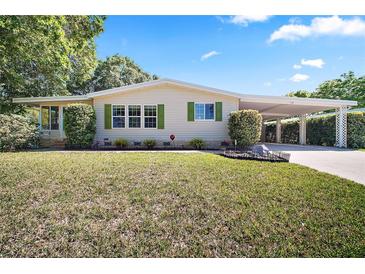 Charming home featuring a covered carport and a well-maintained lawn with lush greenery and manicured shrubs at 3209 Manatee Rd, Tavares, FL 32778