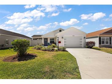 Charming home with a manicured lawn, a two-car garage, and lovely landscaping at 3222 Miller Stachler St, The Villages, FL 32163