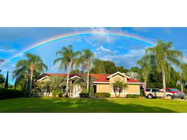 Charming home featuring lush lawn, palm trees, and a vibrant rainbow overhead at 3511 Fox Lake Dr, Apopka, FL 32712