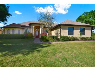 Charming single-story home featuring a well-manicured lawn and a welcoming front entrance with red door at 39705 Grove Hts, Lady Lake, FL 32159