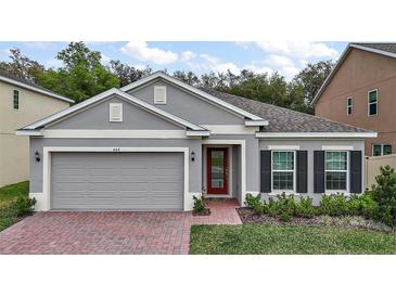 Charming single-story home featuring a brick walkway, gray stucco, and well-maintained landscaping at 444 Shadow Gorge Way, Eustis, FL 32736