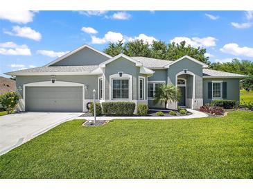 Beautiful single-story home featuring a well-manicured lawn, complemented by a neutral gray exterior and an attached two-car garage at 5557 Freeport Dr, Tavares, FL 32778