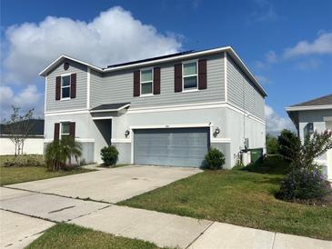 Two-story home featuring gray siding, a two-car garage, and manicured landscaping at 709 Sarner Pass Way, Winter Haven, FL 33881