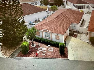 Charming single-story home featuring lush landscaping and a well-maintained yard, and long driveway at 728 Ramirez Ave, The Villages, FL 32159