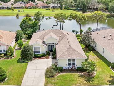 A charming single-story home boasts lush landscaping and a serene lake view with golf course backdrop at 8043 Pine Hollow Dr, Mount Dora, FL 32757