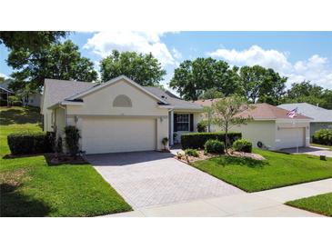 Charming single-story home features a brick driveway and meticulously landscaped front yard, and attached two-car garage at 860 Wolf Creek St, Clermont, FL 34711