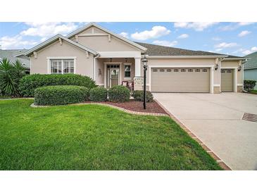 Charming home featuring a well-manicured lawn, mature landscaping, and a two-car garage at 879 Lucky Ln, The Villages, FL 32162