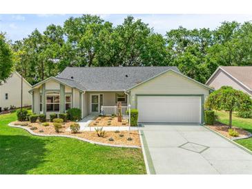 Charming single-story home with a well-manicured lawn, lush landscaping, and a two-car garage at 1061 Soledad Way, The Villages, FL 32159