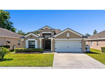 Charming single-story home featuring a well-manicured lawn and an attached two-car garage at 15501 Markham Dr, Clermont, FL 34714