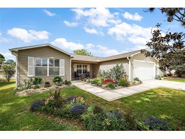 Charming single-story home with well-manicured lawn and colorful landscaping on a sunny day at 299 Jefferson Ln, The Villages, FL 32162