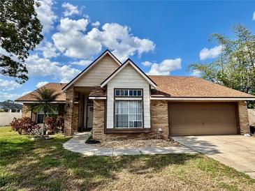 Charming single-story home with a brick exterior, manicured lawn, and attached two-car garage at 3051 Newmark Dr, Deltona, FL 32738
