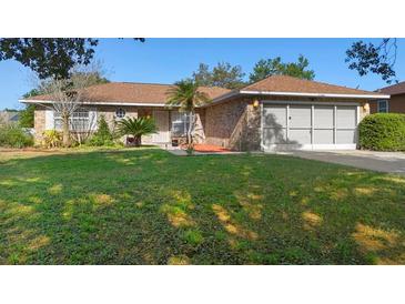 Charming single story home boasts a well-manicured lawn and a classic brick facade with a two car garage at 36545 Scottsdale Dr, Grand Island, FL 32735