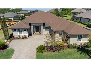 Beautifully landscaped home featuring a brick driveway, neutral tones, and a well maintained lawn at 39505 Hillrise Ln, Lady Lake, FL 32159