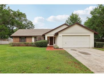 Charming single-story home featuring a well-manicured lawn, brick accents, and an attached two-car garage at 4145 Dora Wood Dr, Mount Dora, FL 32757