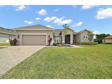 Charming single Gathering home featuring a well-manicured lawn, paver driveway, and two-car garage at 5195 Greens Dr, Lady Lake, FL 32159