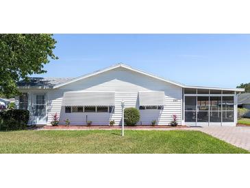 Charming single-story home with a well-maintained lawn, awnings, and enclosed patio at 705 Prado Dr, The Villages, FL 32159