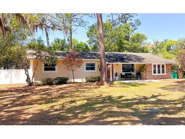 Charming single-story home featuring mature trees, a well-manicured lawn, and a cozy front porch area at 802 Haselton St, Eustis, FL 32726