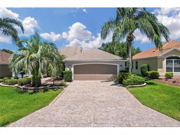 Charming single-story home featuring a paved driveway, lush landscaping and a two-car garage at 9019 Se 177Th Grassmere St, The Villages, FL 32162