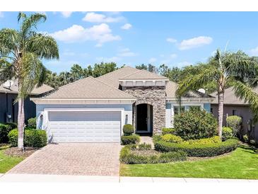 Charming single-story home with a manicured lawn, brick driveway, and a two-car garage surrounded by lush landscaping at 1047 Timbervale Trl, Clermont, FL 34715