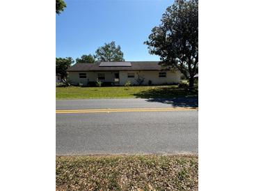 View of a single-story home featuring a well-maintained yard and solar panels on the roof at 10517 52Nd Ct, Belleview, FL 34420