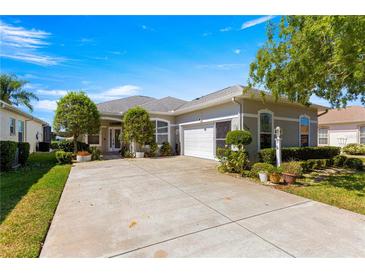 Well-maintained home exterior with a long driveway, lush landscaping, and a two-car garage at 11780 Se 178Th St, Summerfield, FL 34491